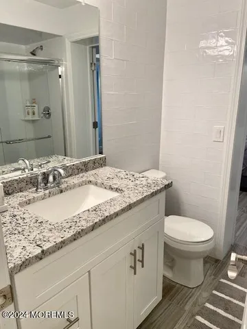 a bathroom with a granite countertop sink a toilet and a mirror