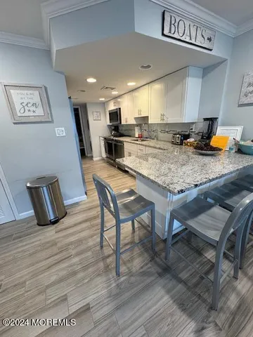 a kitchen with stainless steel appliances granite countertop a table chairs sink and cabinets