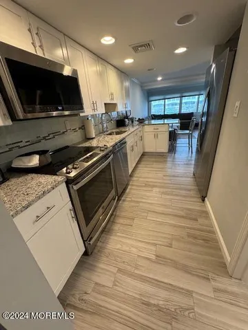 a kitchen with stainless steel appliances kitchen island granite countertop a stove a sink and a microwave