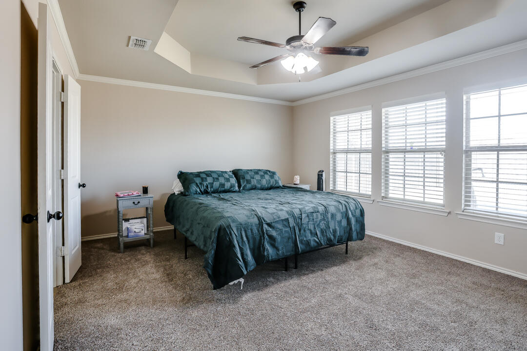6502 71st Street Lubbock, TX 79424 - Photo 12 of 21 a spacious bedroom with a bed and a chandelier