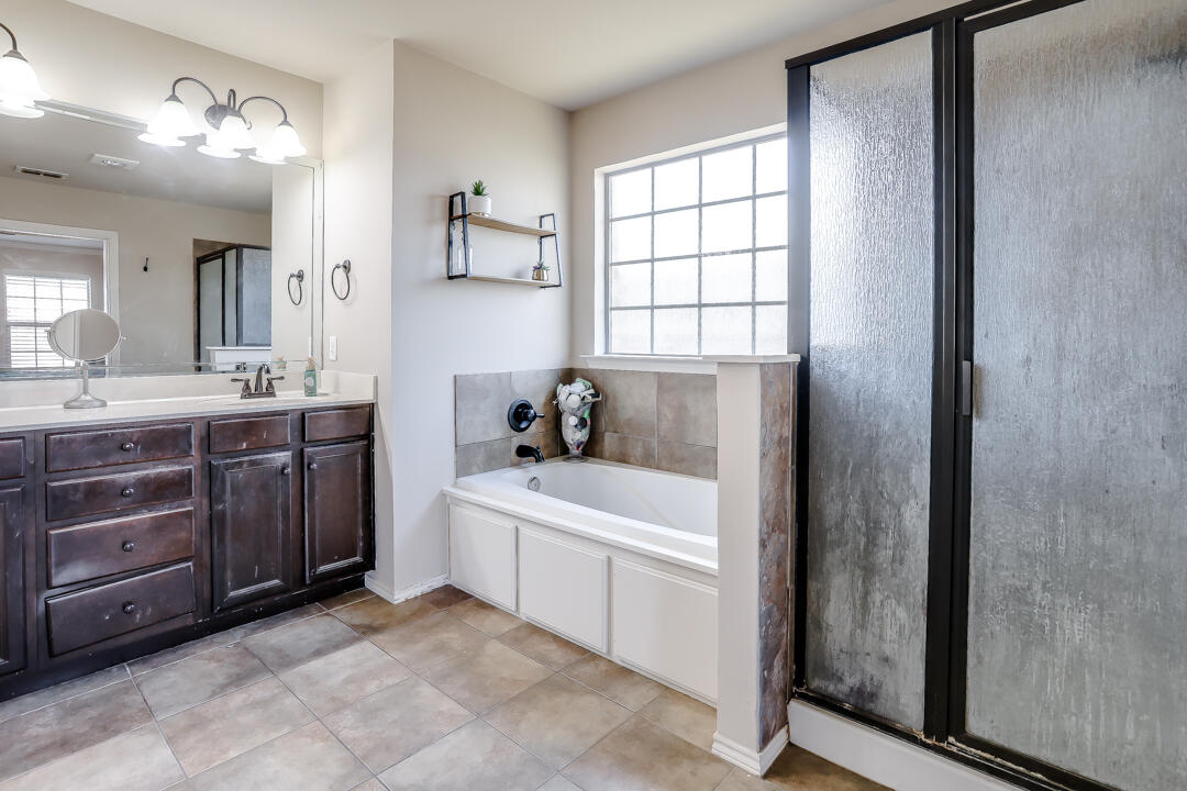 6502 71st Street Lubbock, TX 79424 - Photo 14 of 21 a bathroom with a sink a mirror and a bathtub