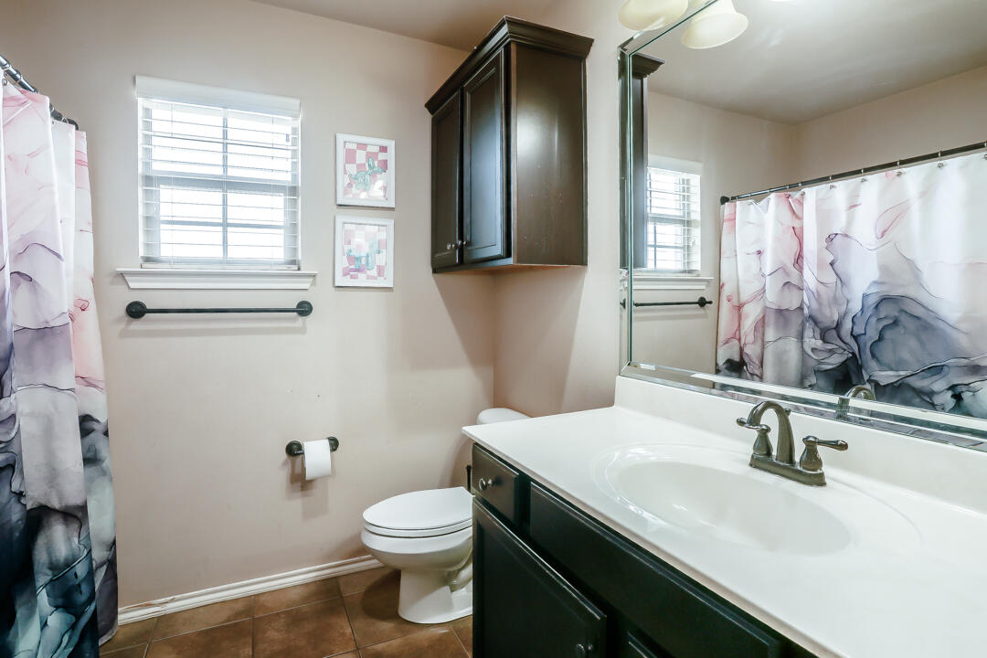 6502 71st Street Lubbock, TX 79424 - Photo 17 of 21 a bathroom with a sink toilet and mirror