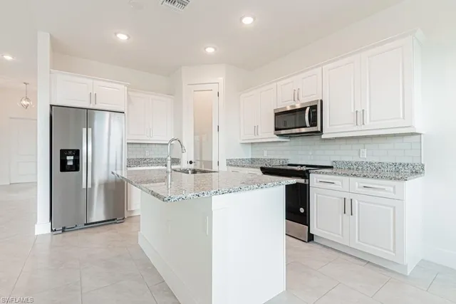 a kitchen with stainless steel appliances granite countertop a stove top oven a refrigerator and white cabinets
