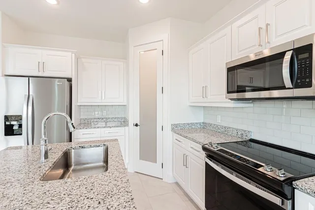 a kitchen with granite countertop a stove a sink and a microwave