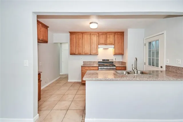 a kitchen with granite countertop a sink cabinets and stainless steel appliances