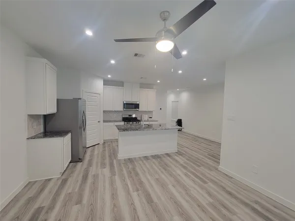 a large white kitchen with kitchen island a sink a stove and a refrigerator
