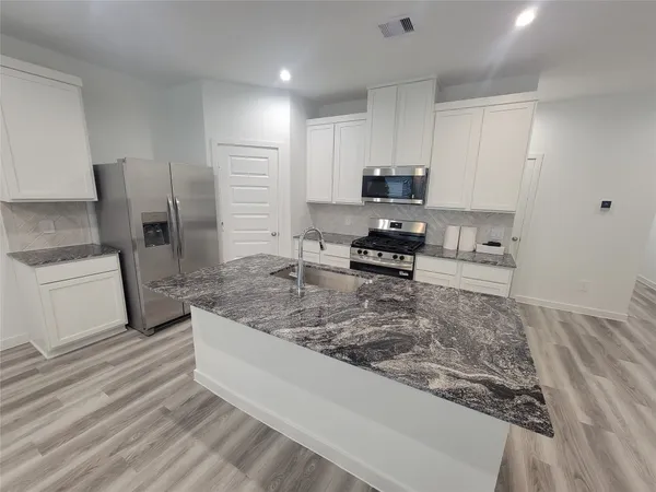 a kitchen with stainless steel appliances granite countertop a sink stove and refrigerator