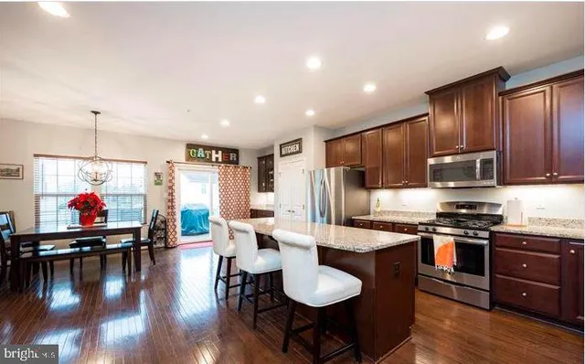 a kitchen with stainless steel appliances kitchen island granite countertop a stove a sink a refrigerator and chairs