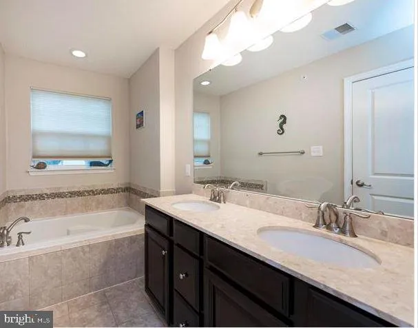 a bathroom with a granite countertop bathtub sink double and mirror