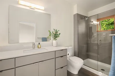 a bathroom with a shower sink vanity mirror and toilet