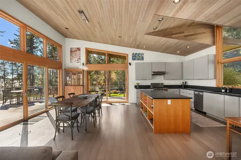 a kitchen with stainless steel appliances granite countertop a stove top oven a dining table and chairs with wooden floor