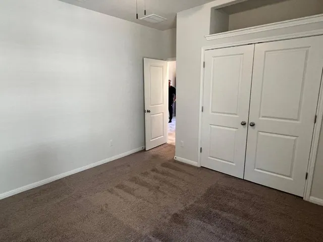 a view of an empty room with window and chandelier fan