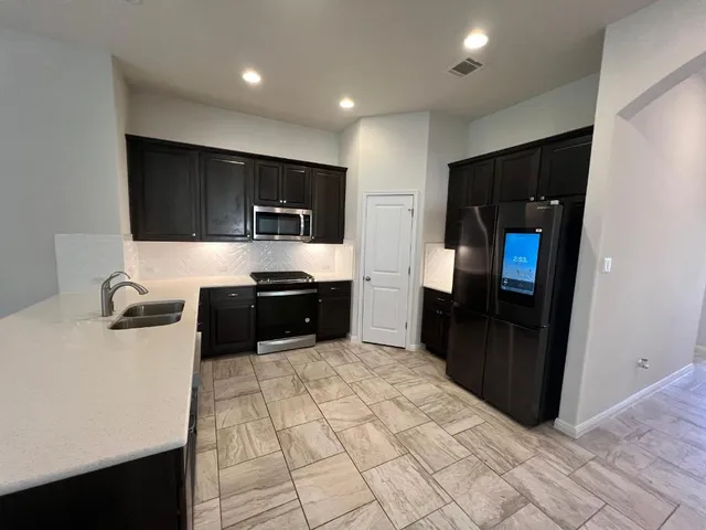 a large kitchen with stainless steel appliances a refrigerator and a sink