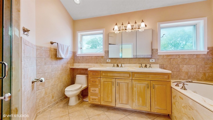 240 Hibbard Road Wilmette, IL 60091 - Photo 19 of 42 a bathroom with a sink and mirror with bathtub