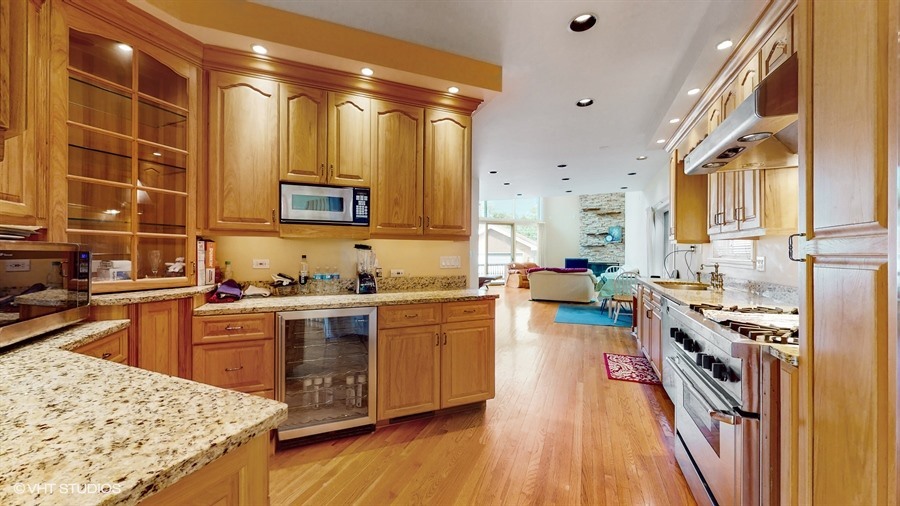 240 Hibbard Road Wilmette, IL 60091 - Photo 9 of 42 a kitchen with stainless steel appliances granite countertop hardwood floor sink stove and wooden cabinets