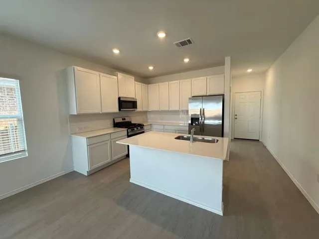 a kitchen with stainless steel appliances granite countertop a sink stove and refrigerator