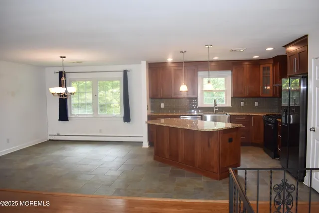 a view of kitchen with granite countertop window sink and refrigerator