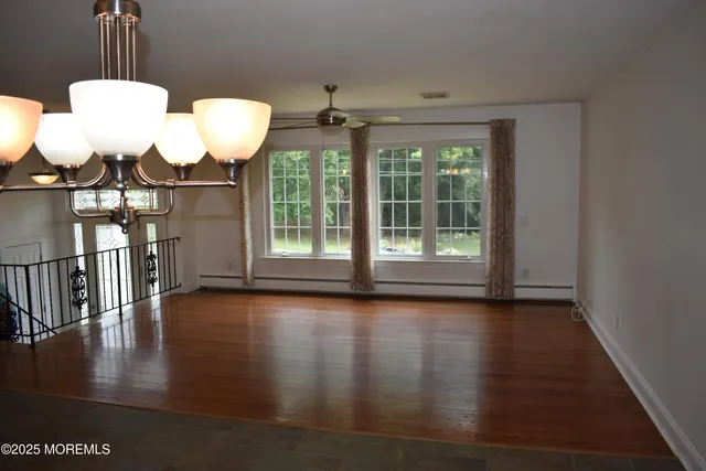 a view of an empty room with wooden floor and window