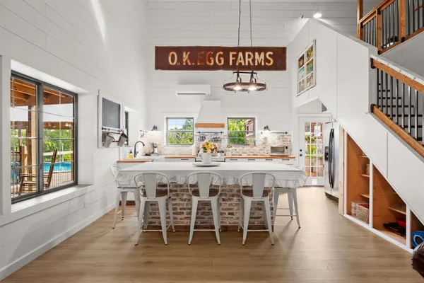a dining hall with stainless steel appliances kitchen island granite countertop a table chairs and a large window