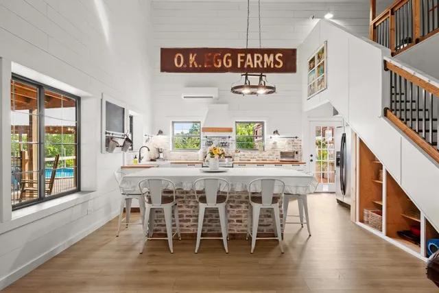 a dining hall with stainless steel appliances kitchen island granite countertop a table chairs and a large window