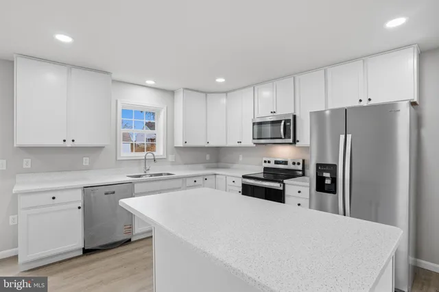 a kitchen with a sink a stove a refrigerator a center island and a window