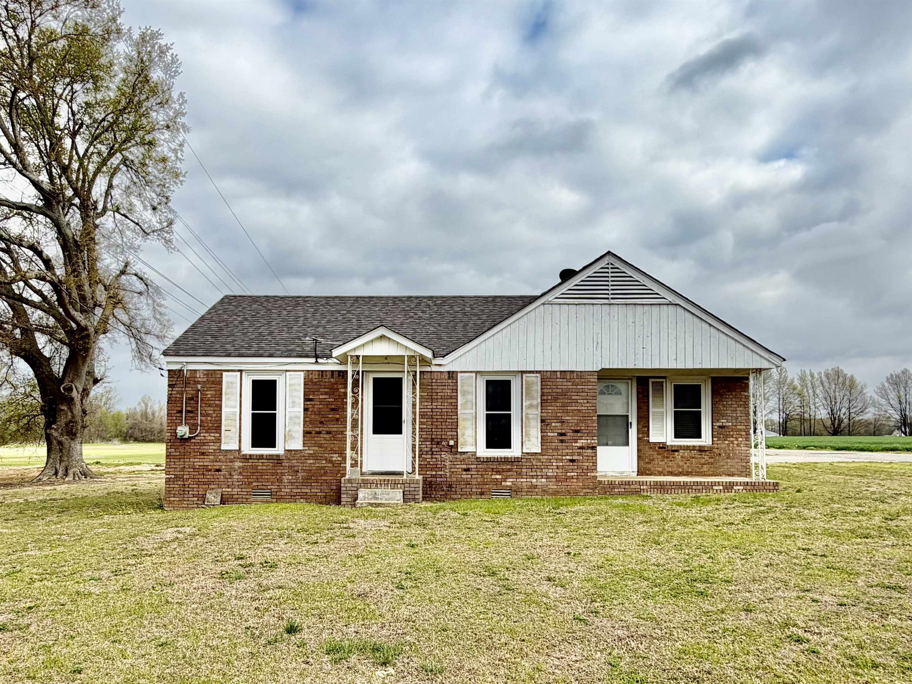 View of front of property featuring brick siding, a front yard, crawl space, and roof with shingles