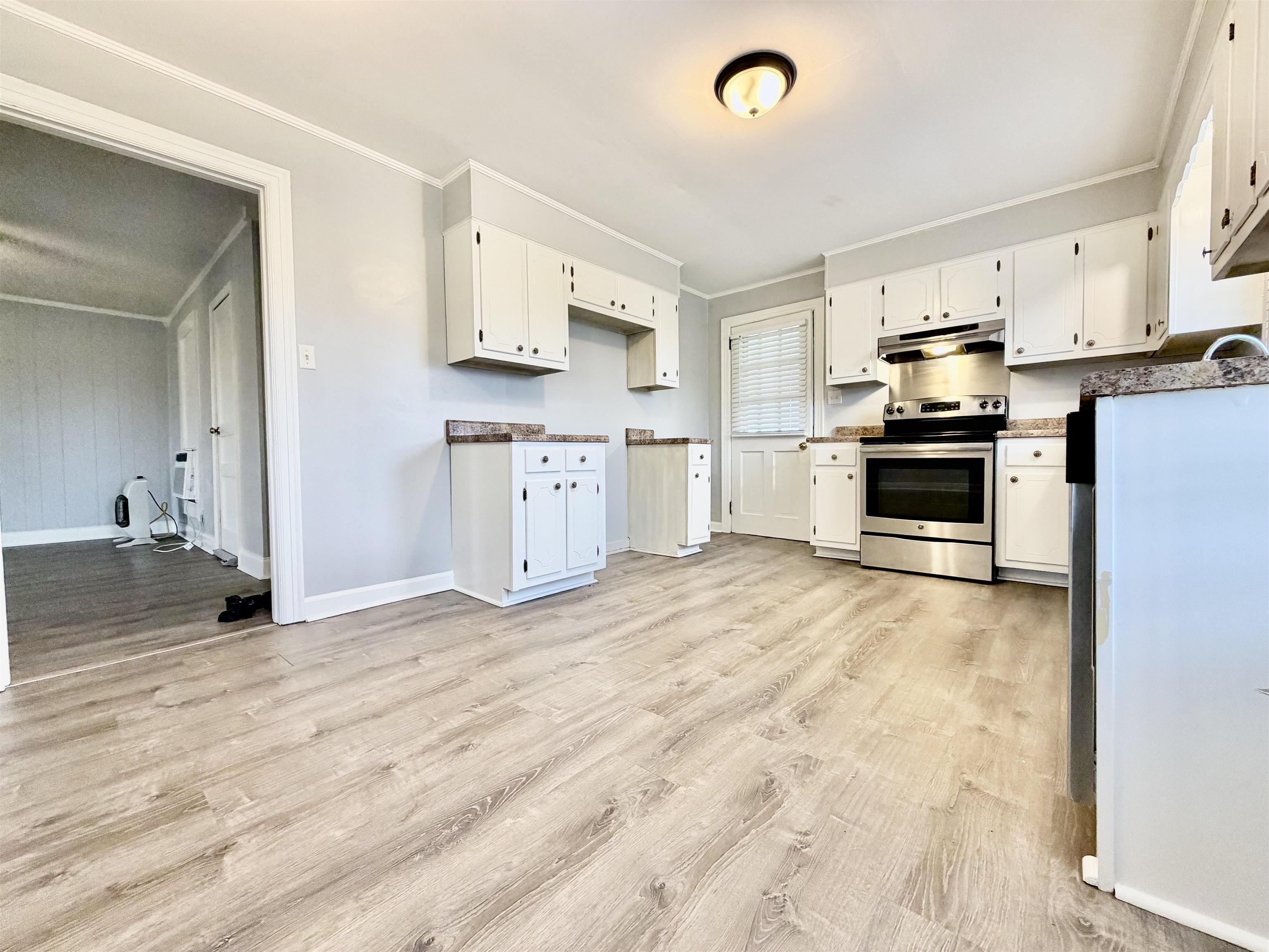 5442 Bride Road Covington, TN 38019 - Photo 12 of 19 Kitchen with ornamental molding, stainless steel electric range, white cabinetry, and light wood-type flooring