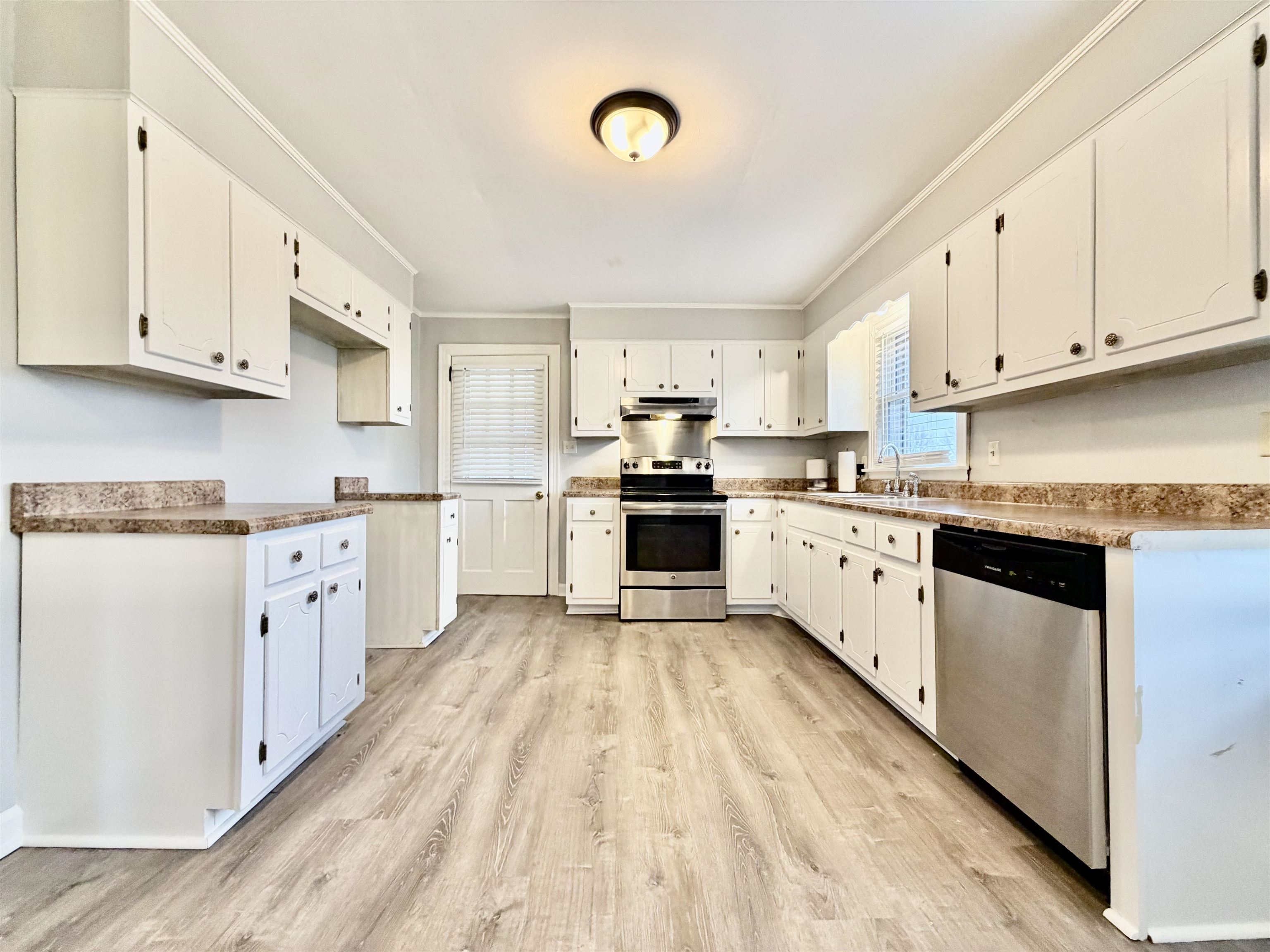 5442 Bride Road Covington, TN 38019 - Photo 9 of 19 Kitchen with stainless steel appliances, crown molding, light wood finished floors, and white cabinets