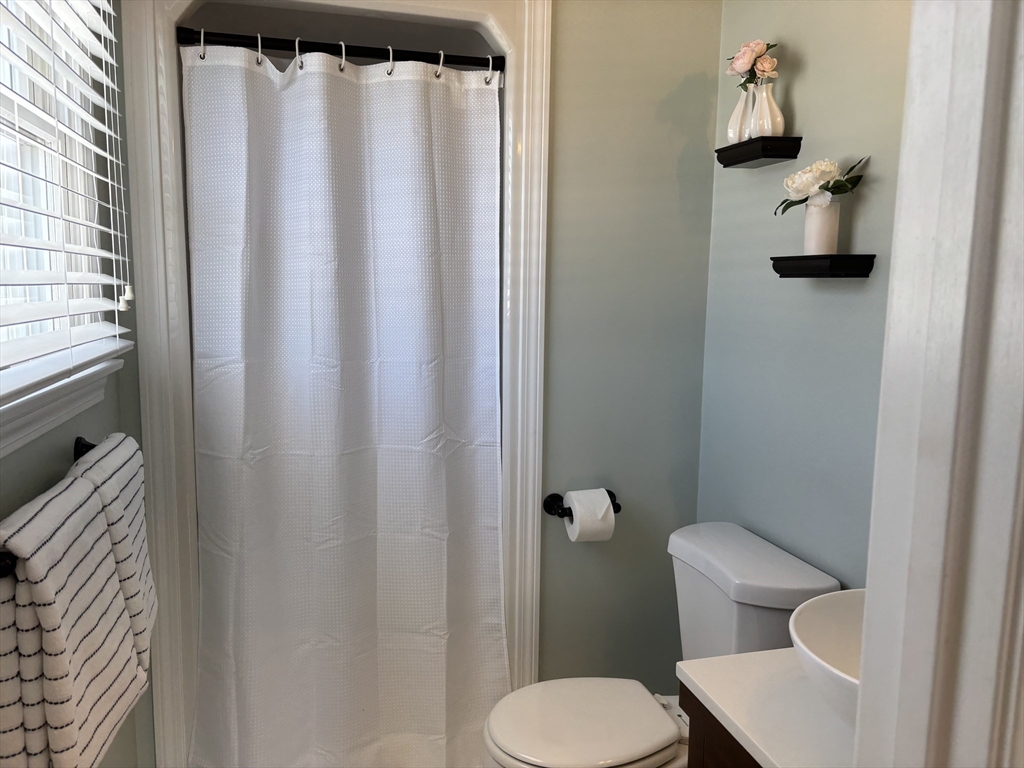 56 Glenwood Road Rutland, MA 01543 - Photo 19 of 41 a white toilet sitting next to a shower curtain