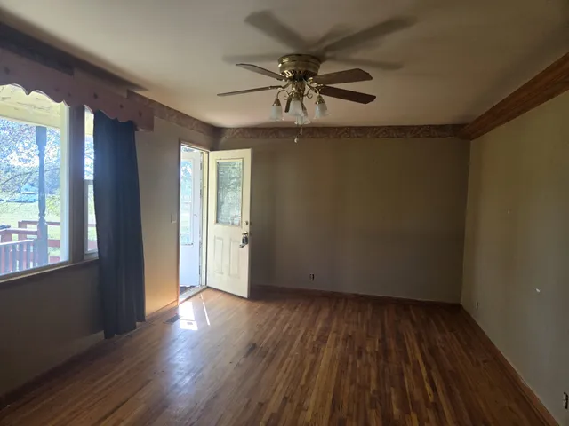 a view of an empty room with wooden floor and a window