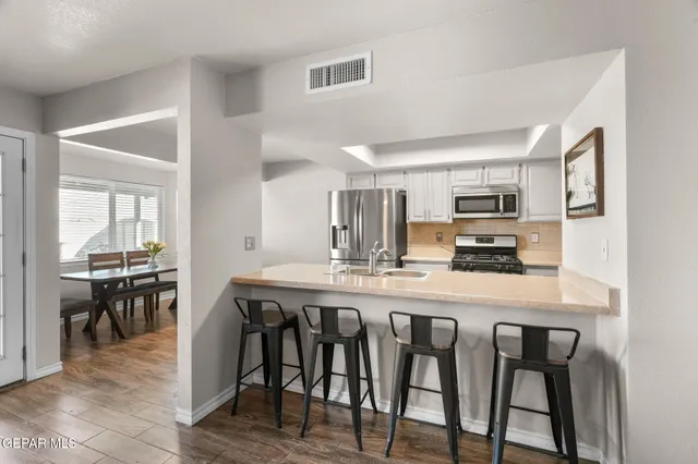 a kitchen with stainless steel appliances a table and chairs in it