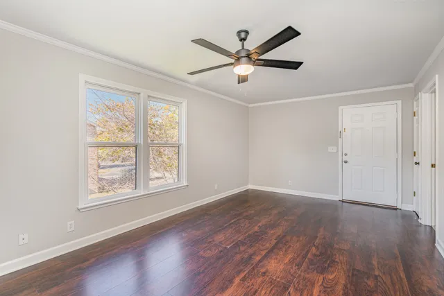 a view of an empty room with wooden floor and a window