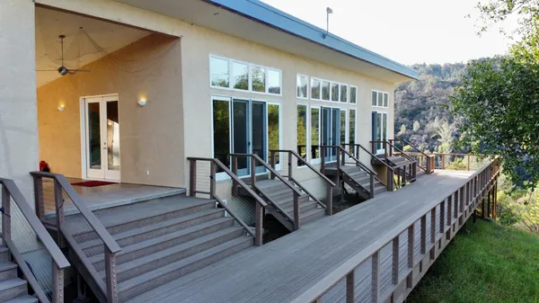 a view of a house with wooden deck and furniture