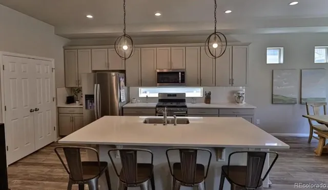 a kitchen with stainless steel appliances a table chairs refrigerator and microwave