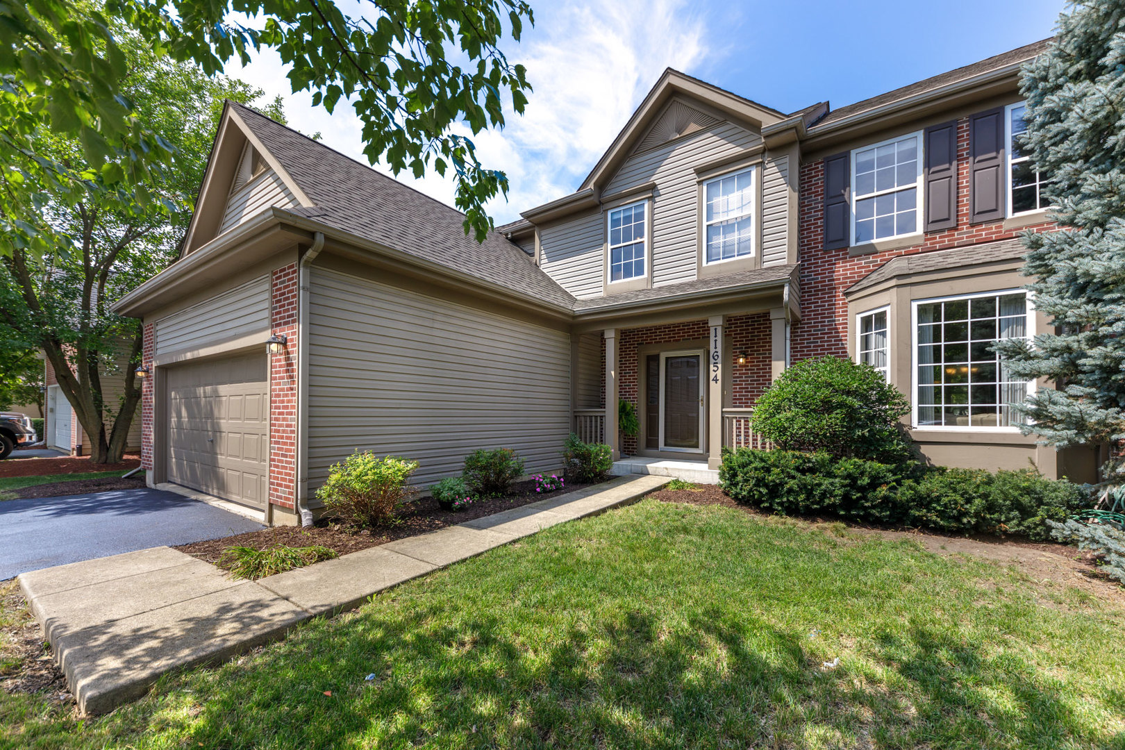 11654 Olympic Drive Plainfield, IL 60585 - Photo 2 of 25 a front view of a house with a garden