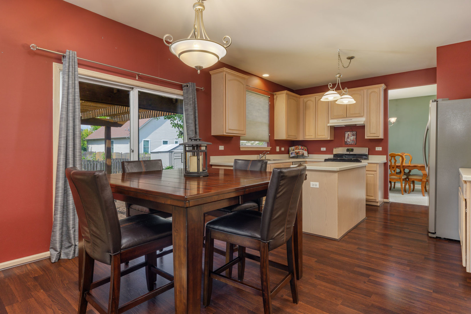 11654 Olympic Drive Plainfield, IL 60585 - Photo 4 of 25 a kitchen with stainless steel appliances granite countertop a stove a refrigerator a kitchen island a dining table and chairs with wooden floor