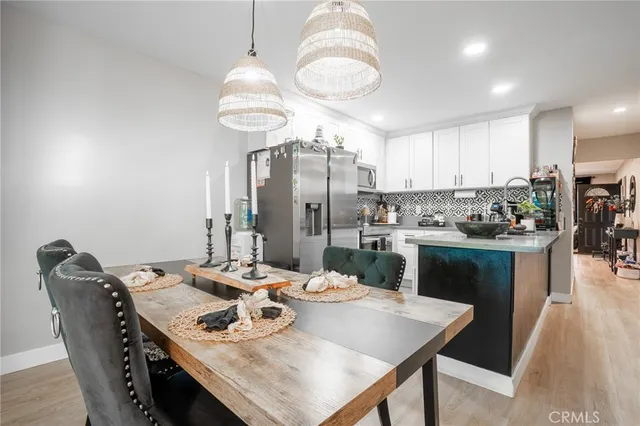 a kitchen with stainless steel appliances granite countertop a dining table chairs and chandelier