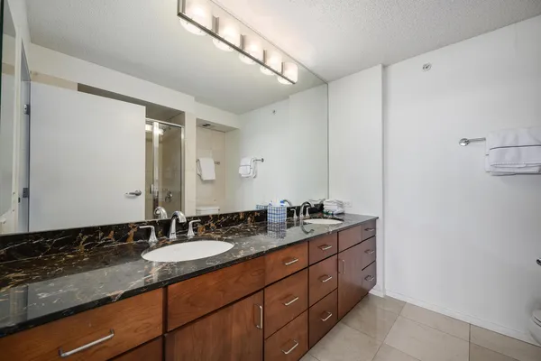 a bathroom with a granite countertop double vanity sink and mirror
