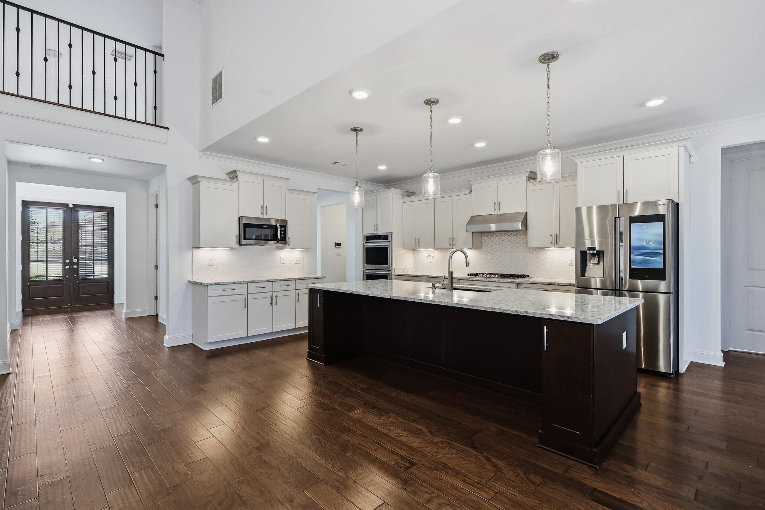 496 Fallen Timbers Cove Collierville, TN 38017 - Photo 9 of 40 Two tone kitchen with stainless steel appliances, french doors, dark wood-type flooring, an island with sink, and tasteful backsplash