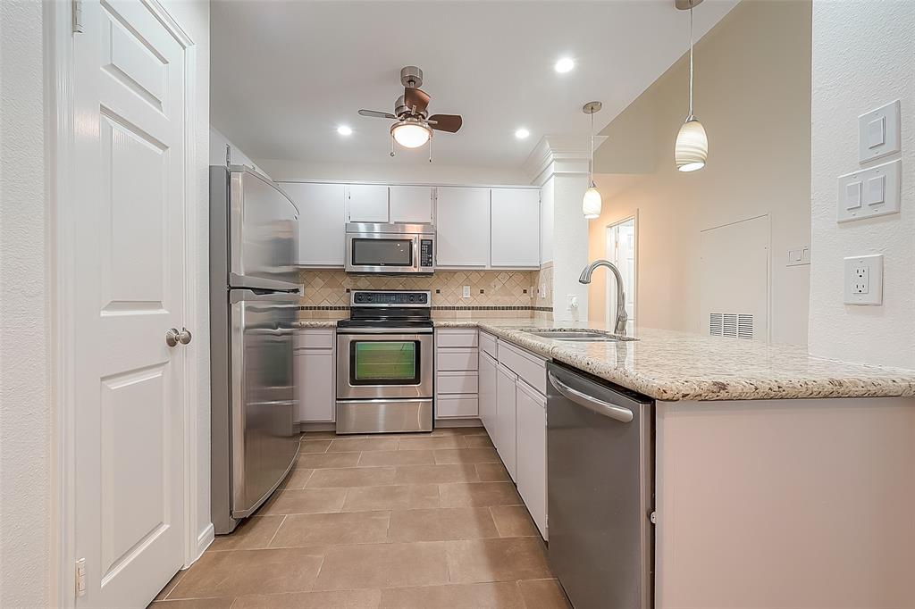 a kitchen with kitchen island granite countertop stainless steel appliances cabinets a sink and a counter top space