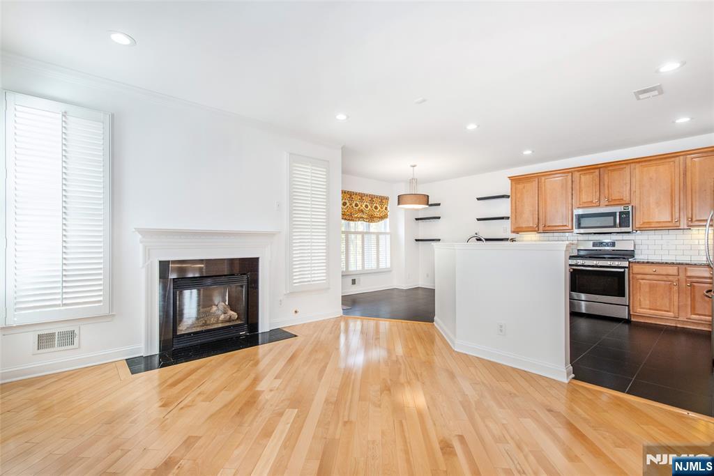 43 South Shore Drive, Unit 81 South Amboy, NJ 08879 - Photo 11 of 30 a kitchen with stainless steel appliances a stove top oven a sink dishwasher and a fireplace with wooden floor