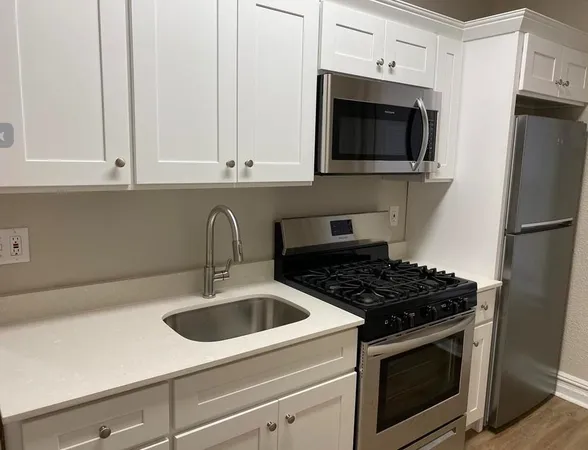 a kitchen with stainless steel appliances granite countertop white cabinets a stove a microwave and a refrigerator