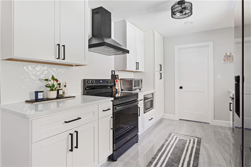 5925 Old Bill Cook Road Atlanta, GA 30349 - Photo 4 of 49 a kitchen with white cabinets and stainless steel appliances