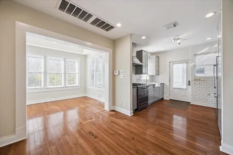 a view of an empty room with wooden floor and windows