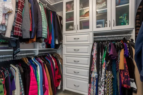 a view of walk in closet with clothes and shoes