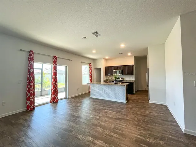 a large space with kitchen island stainless steel appliances wooden floor and window