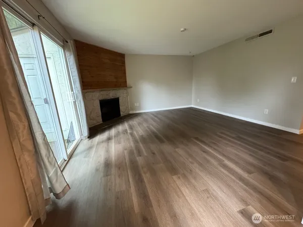 a view of empty room with wooden floor and fireplace