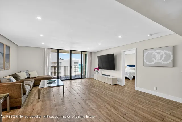 a living room with furniture a flat screen tv and a floor to ceiling window