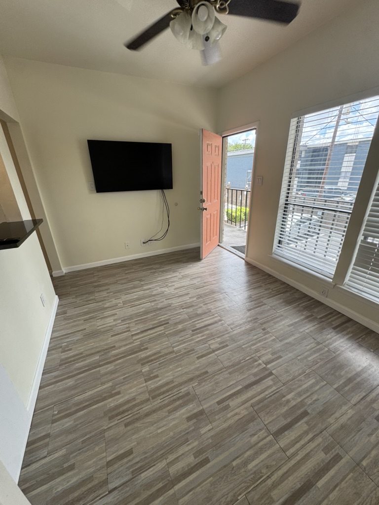 a view of an empty room with wooden floor and a window