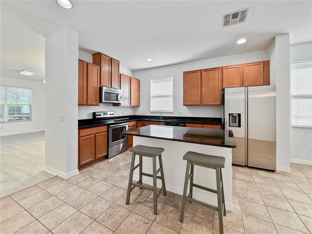 a kitchen with stainless steel appliances granite countertop a stove a sink a microwave and a refrigerator